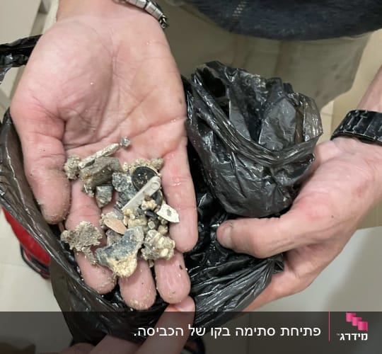 ידיים מחזיקות שברי צינורות בשקית שחורה